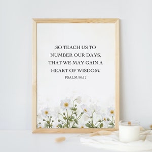 May include: A framed print with a white background and white flowers. The print features the text "SO TEACH US TO NUMBER OUR DAYS, THAT WE MAY GAIN A HEART OF WISDOM. PSALM 90:12".