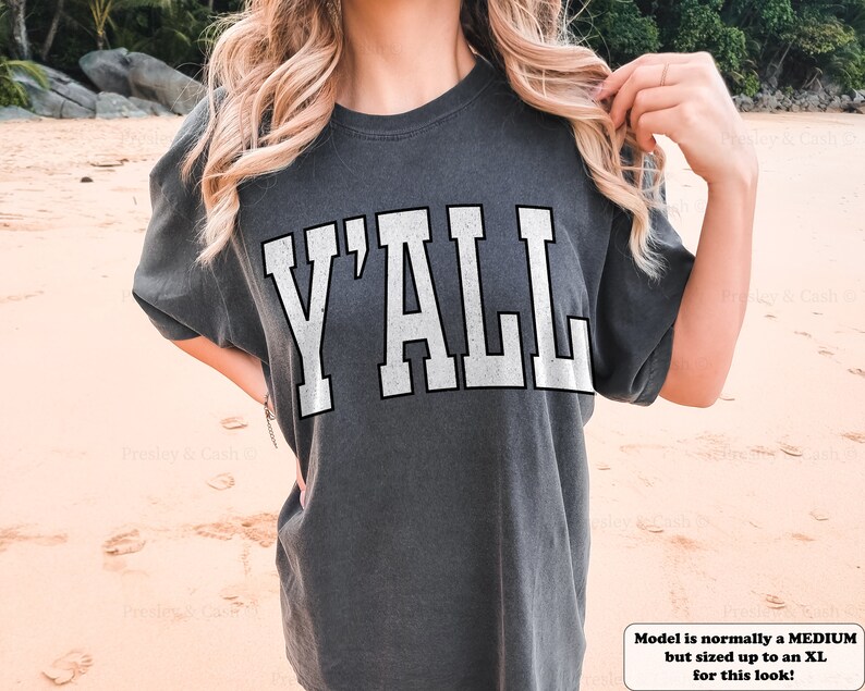 May include: A gray t-shirt with the word "Y'ALL" printed in white on the front. The model is wearing a size XL, but normally wears a medium.