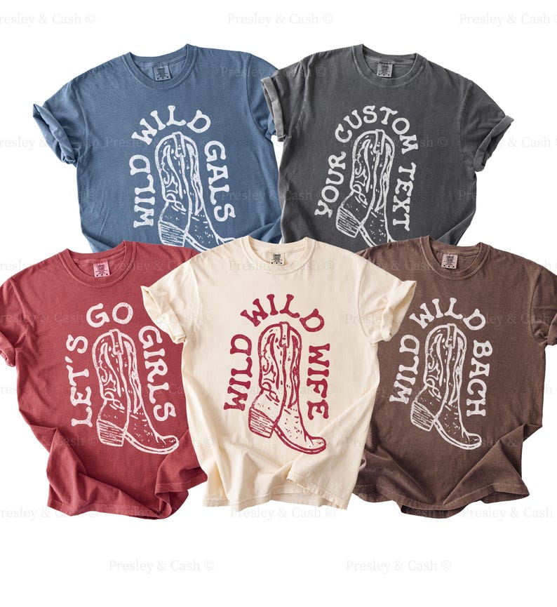 Flat lay of western bachelorette shirts in a variety of colors and sayings, including “Wild Wild Wife,” “Wild Wild Bach,” “Wild Wild Gals,” and “Let’s Go Girls.” Perfect for country-themed bachelorette parties or group gifts.