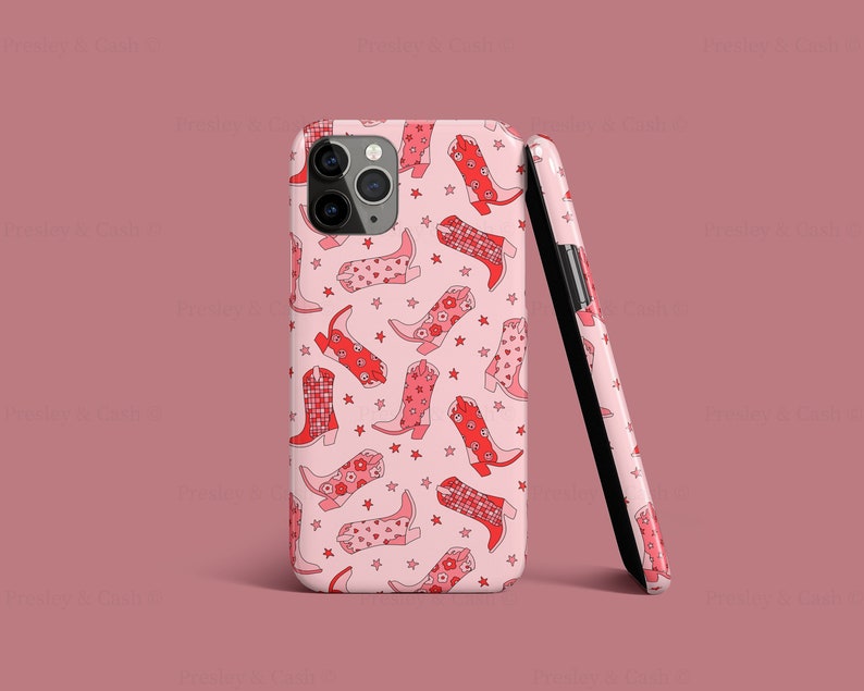 May include: A pink iPhone case with a pattern of red cowboy boots and white stars.