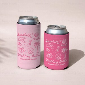 Two pink can coolers in slim and regular sizes, each with “Seashells and Wedding Bells” printed in white and red. Coastal bachelorette design includes seashells, waves, and tropical details.