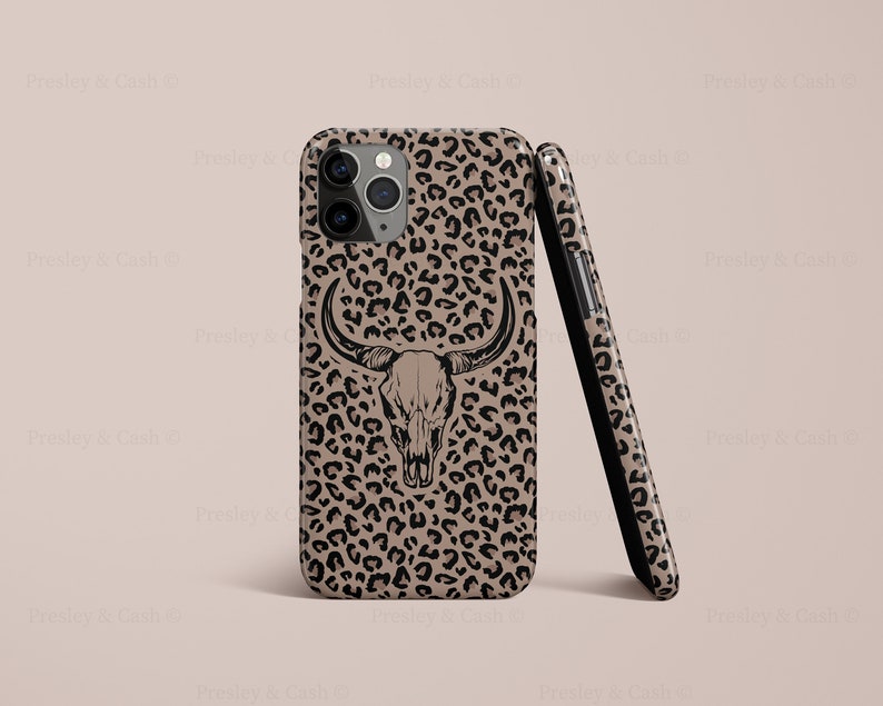 May include: A black and brown phone case with a leopard print design and a black skull with horns in the center.