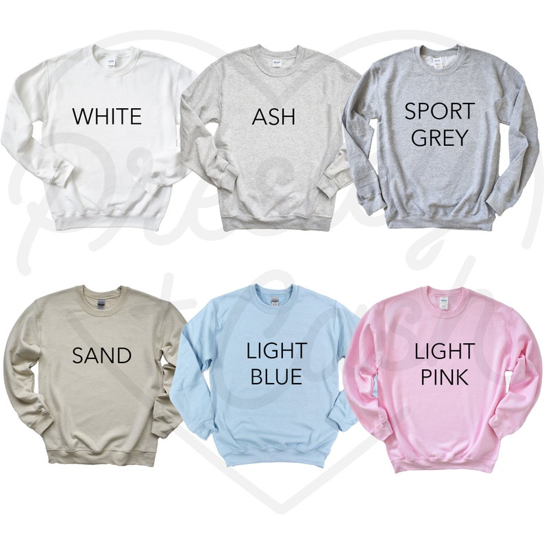 May include: Six crew neck sweatshirts in various colors: white, ash, sport grey, sand, light blue, and light pink. Each sweatshirt has the color name printed in black block letters across the front.