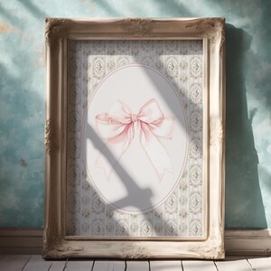 May include: A framed print of a pink bow on a white background with a floral pattern. The bow is tied with a ribbon and has a delicate, feminine look.