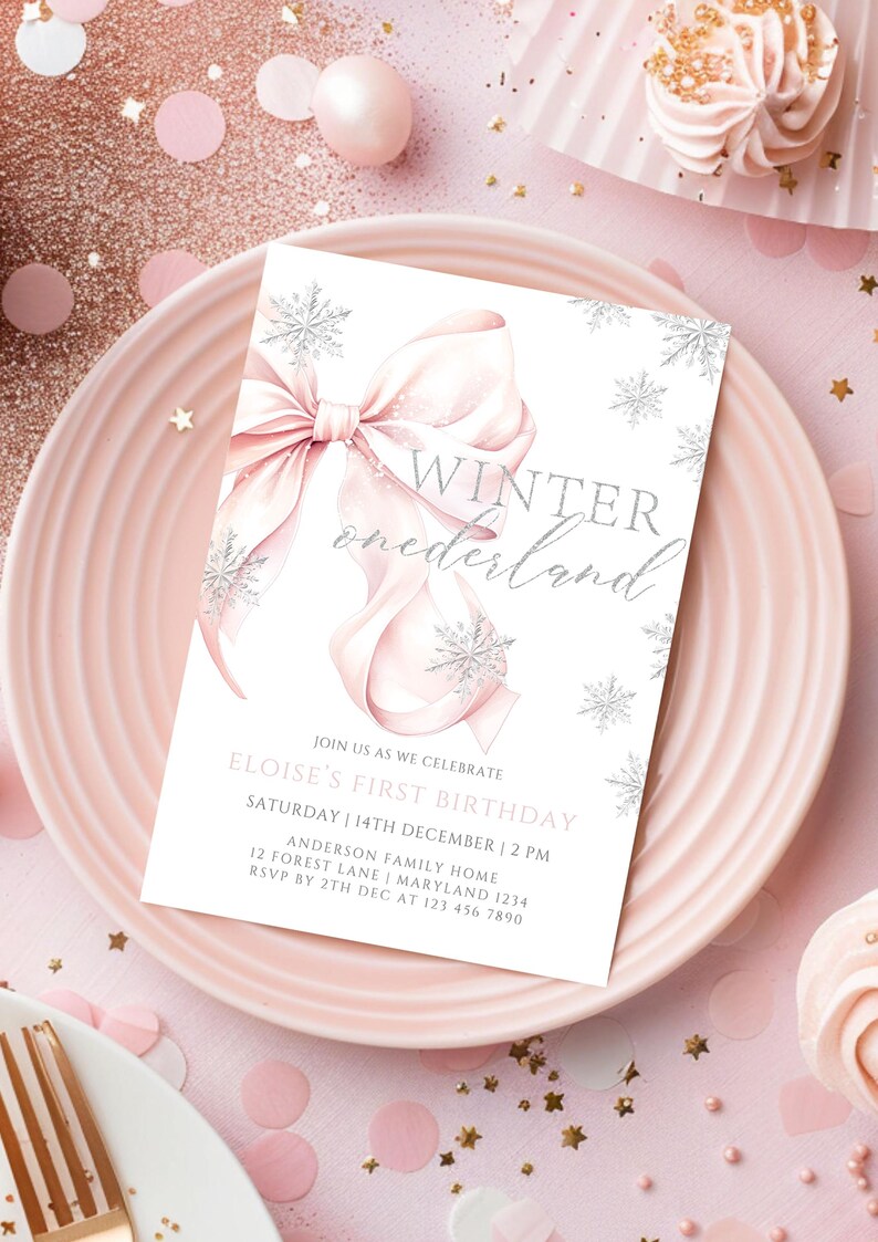 May include: A white invitation card with a pink bow and silver snowflakes. The text on the card reads "Winter onederland" and includes details for Eloise's first birthday party.
