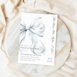 May include: A white bridal shower invitation with a watercolor illustration of a large white bow. The text reads "Something Blue Before Do!" and includes the bride's name, date, time, and RSVP information.