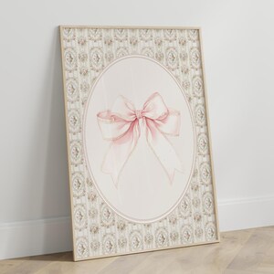 May include: A framed print with a pink bow on a white background. The frame has a decorative border with a floral pattern.
