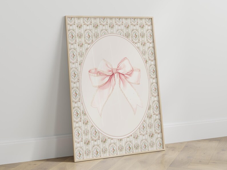 May include: A framed print with a pink bow on a white background. The frame has a decorative border with a floral pattern.