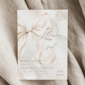 May include: A white and beige baby shower invitation with a large white bow and the text "Heaven sent" in cursive. The invitation includes the details of the event, including the date, time, and location.