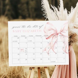 May include: A white calendar on an easel with a pink bow graphic, designed for a baby shower. The calendar displays the months of September and October, with the text "guess the due date of BABY ELIZABETH."