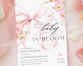Puede incluir: Una invitación a un baby shower con un gran lazo rosa y detalles florales. Las palabras "baby in bloom" están escritas en una fuente elegante. El texto incluye los detalles del evento, como el nombre del invitado, la fecha y la hora.