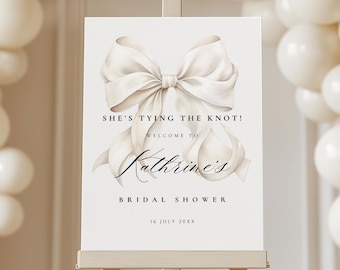 May include: White bridal shower sign featuring a large white bow and the text "She's tying the knot! Welcome to Kathrine's Bridal Shower 16 July 20XX"