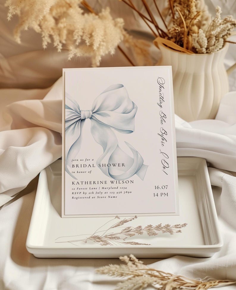 May include: A blue and white bridal shower invitation with a watercolor illustration of a bow. The invitation reads "Something Blue Before Do!" and includes the text "Join us for a Bridal Shower in honor of Katherine Wilson" and the date and time of the event.