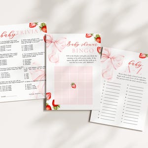 May include: Three baby shower game sheets with strawberry and bow accents. The games include trivia, bingo, and an A-Z game. The text on the sheets includes "baby trivia", "baby shower bingo", and "baby A-Z". The color scheme is primarily pink and white.