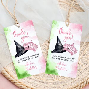 May include: Two thank you tags with a witch's hat and a pink crown on a watercolor background. The text on the tags reads "Thank you!" and "Thank you for making my birthday wickedly fun! with love, Charlotte's".