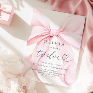 May include: A rectangular invitation card featuring a large, soft pink ribbon bow graphic. The text reads: OLIVIA IS TURNING twelve, JOIN US TO CELEBRATE, SATURDAY | 16TH JULY 2025 | 2 PM, LAUREN'S HOME, BOWTIFUL LANE, 123 RIBBONLAND, RSVP BY 2ND AUGUST AT 123 456 7890.