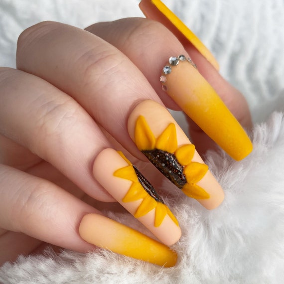 Premium Photo | A woman with sunflower nails painted with white and yellow  flowers