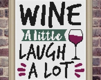 May include: A framed cross-stitch design with the text "Wine a little laugh a lot" and a red wine glass graphic.
