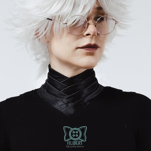 May include: A black long-sleeved shirt featuring a high, crisscross-layered collar design. The garment includes a light blue logo on the chest depicting a stylized bow tie with a four-hole button in the center and the text FILIBERT high quality patterns.
