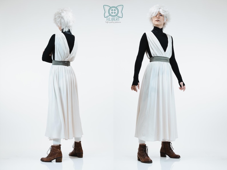 May include: A white sleeveless dress with a deep V-neckline and a wide grey waistband, worn over a black long-sleeved turtleneck shirt. The outfit includes white leggings and brown lace-up boots. The Filibert logo is visible at the top center.