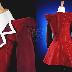 May include: A red jacket with a white collar and a fitted silhouette. The jacket has a unique design with a pointed collar and a flared hem. The jacket is made of a soft, comfortable fabric and has a classic look.