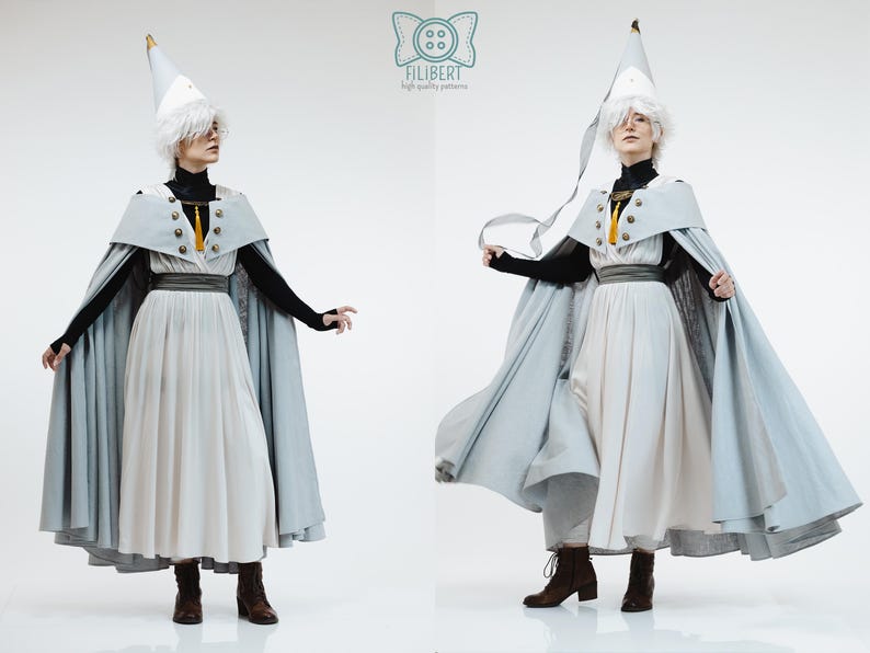 May include: A costume set featuring a light blue cape with gold buttons and a yellow tassel, a white pleated skirt, a black long-sleeved top, and a pointed white hat. The Filibert logo is visible at the top center of the image.