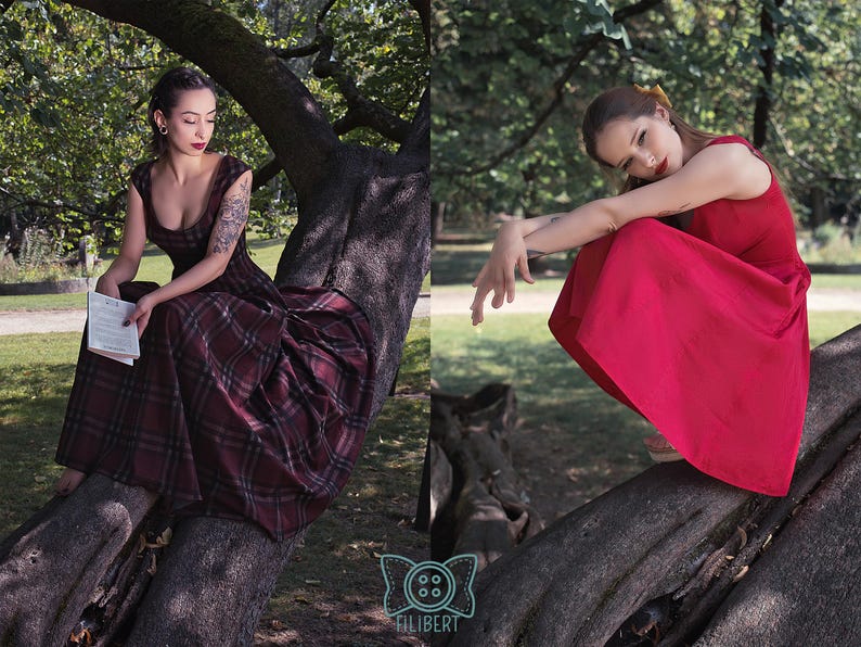 May include: Two women wearing dresses are sitting on a tree branch in a park. One woman is wearing a burgundy plaid dress, and the other is wearing a red dress. The dresses are the focal point of the image, showcasing their design and color.