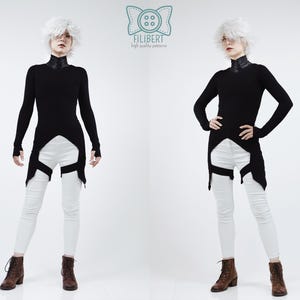 May include: A long-sleeved black tunic with a high collar and a pointed hemline, paired with white skinny trousers featuring black leg straps. The garment is displayed with a logo at the top center containing a button icon and the text FILIBERT.