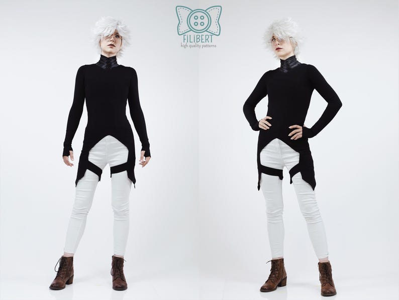 May include: A long-sleeved black tunic with a high collar and a pointed hemline, paired with white skinny trousers featuring black leg straps. The garment is displayed with a logo at the top center containing a button icon and the text FILIBERT.