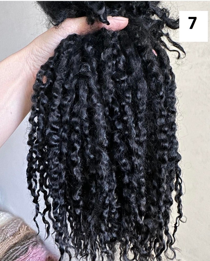 Peut inclure: Un paquet d'extensions de cheveux noirs pr&eacute;sentant des boucles en spirale serr&eacute;es et d&eacute;finies. Les cheveux ont une texture sombre et brillante avec des motifs en spirale uniformes sur toute la longueur. Le chiffre 7 est affich&eacute; dans un encadr&eacute; blanc.