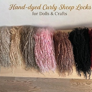 May include: A collection of hand-dyed curly sheep locks arranged in a row, featuring colours including white, beige, grey, pink, brown, black, and deep red. The text "Hand-dyed Curly Sheep Locks for Dolls & Crafts" is visible at the top.