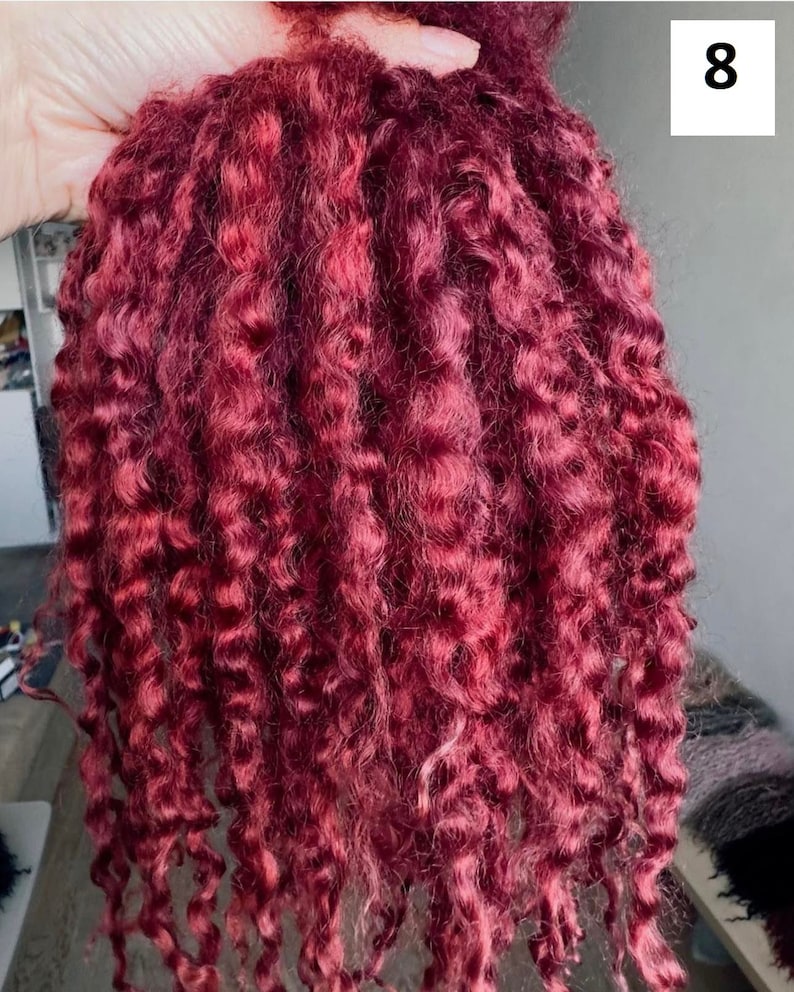 Peut inclure: Un paquet d'extensions de cheveux rouge bordeaux profond pr&eacute;sentant une texture serr&eacute;e, enroul&eacute;e et boucl&eacute;e. Les m&egrave;ches de cheveux sont de couleur uniforme et dispos&eacute;es en longues boucles en cascade tombant verticalement.