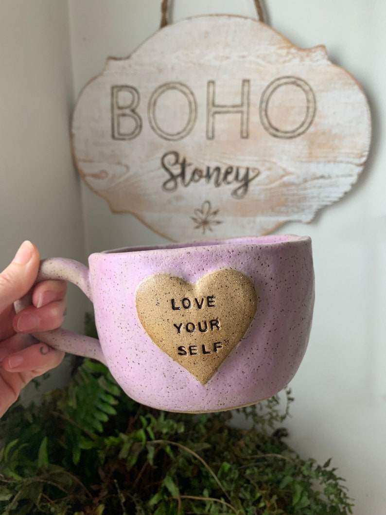 May include: Purple ceramic mug with a heart-shaped design that says "Love Your Self".