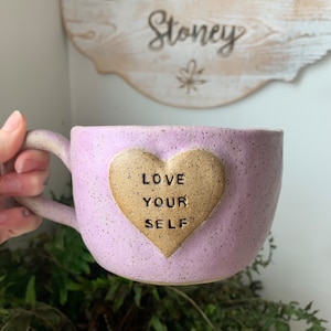 May include: Purple ceramic mug with a gold heart that says "Love Your Self" on it.