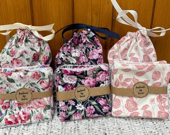May include: Three sets of handmade reusable cotton rounds in floral patterns. The rounds are packaged in white cotton drawstring bags with brown paper tags that say "handmade by Soussew".