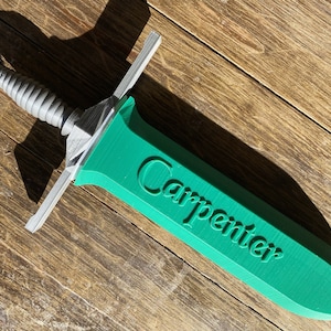 May include: A green plastic sword with a silver handle. The word "Carpenter" is printed on the blade.
