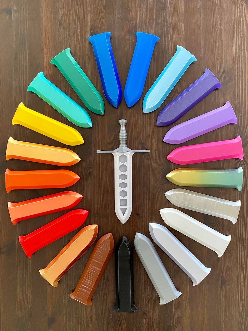 May include: A silver sword with a black handle surrounded by 20 colorful plastic sword replicas arranged in a circle. The replicas are in shades of blue, green, yellow, orange, red, brown, and gray.