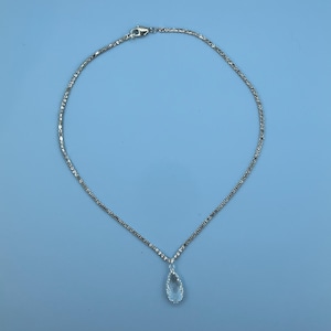 May include: A silver chain necklace with a teardrop-shaped pendant featuring a clear crystal.