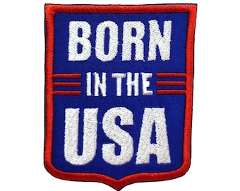 以下が含まれることがあります： 白文字で「Born in the USA」と書かれた、青と赤の刺繍パッチ