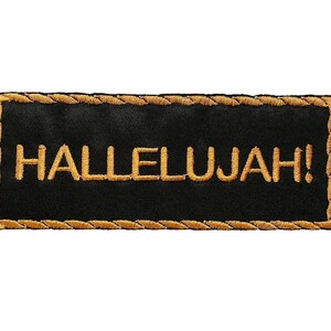 Może przedstawiać: Czarna naszywka haftowana ze złotą obwódką i napisem "HALLELUJAH!" haftowanym złotą nicią.