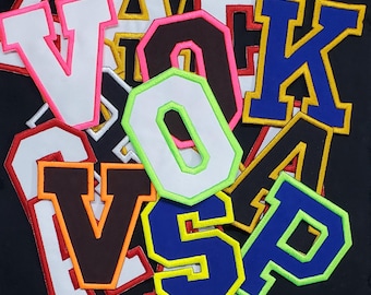 May include: Assortment of felt letter patches in various colors, including white, black, blue, green, and red. The letters are outlined in a contrasting color. The letters are V, O, K, A, S, and P.