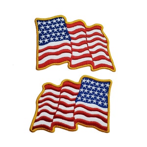 Può includere: Due toppe ricamate con la bandiera americana con contorno dorato. Le bandiere sventolano e hanno strisce rosse e bianche con stelle blu.