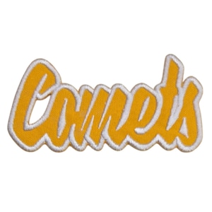 May include: A yellow embroidered patch with the word "Comets" in a cursive font. The lettering is outlined in white, creating a contrasting border. The patch is likely for apparel or accessories.