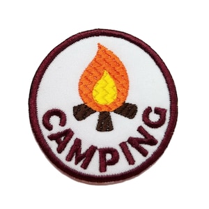 May include: A white embroidered patch with a maroon border. The patch features a stylized orange and yellow campfire with the word "CAMPING" in maroon embroidery around the campfire.