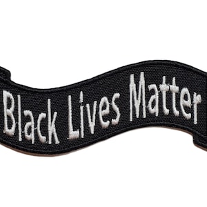Könnte beinhalten: Schwarzer Banner mit weißer Stickerei, auf dem "Black Lives Matter" gestickt ist.