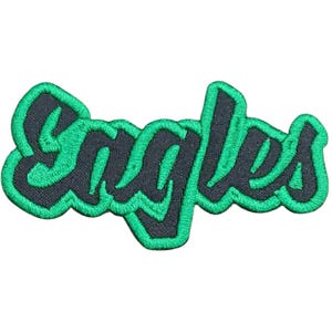 May include: Embroidered patch featuring the word "Eagles" in a stylized, cursive font. The text is in dark gray with a bright green outline and border. The patch is likely for apparel or accessories.