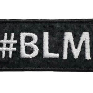 Puede incluir: Parche de tela negro con texto bordado en blanco que dice "#BLM".