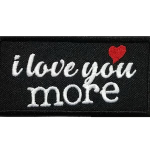 May include: Black rectangular patch embroidered with the phrase "i love you more" in white script. A small red heart is above the word "you". The patch is a romantic gift.