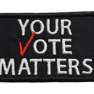 May include: Black embroidered patch with white text that reads "YOUR VOTE MATTERS" and a red checkmark.