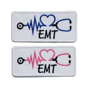 May include: Two white embroidered patches with a heart, EKG line, and stethoscope. The text "EMT" is below the design. One patch has a blue stethoscope and heart, the other has a pink stethoscope and heart.